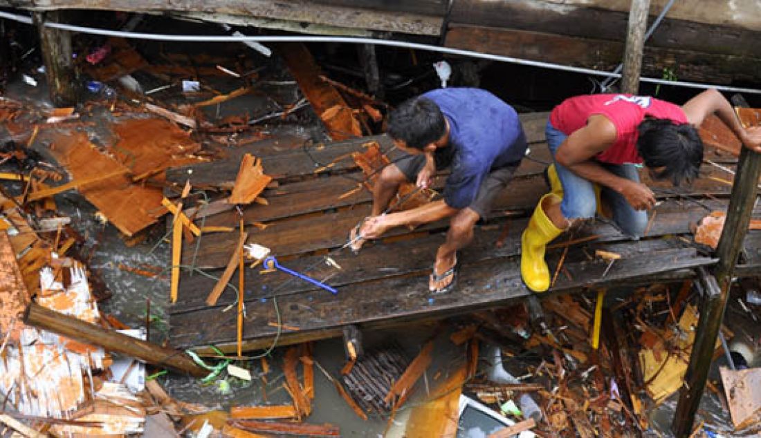 Warga Batumerah, Batuampar, mengangkat puing-puing rumah mereka yang diterjang ombak besar, Senin (8/2). Sebanyak 20 rumah hanyut dan 47 rumah rusak. Foto: Ist - JPNN.com