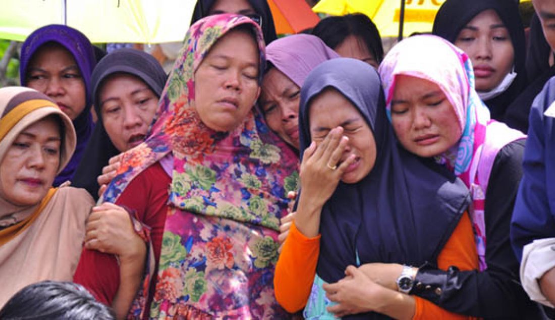 Ibunda almarhum Feby, Nurcahaya Ningsih (kiri) tidak tahan menahan tangis hingga badannya lemas saat melihat pemakaman anaknya di Taman Pemakaman Umum (TPU) Taman Langgeng, Seipanas, Batam, Rabu (4/5). Foto: Ist - JPNN.com