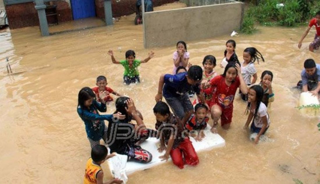 Anak-anak warga Taman Laguna, Kelurahan Tanjungriau, Sekupang bermain air hujan yang mengakibatkan banjir di Peruamhan ini sampai satu meter, Minggu (13/12). Foto: Dalil/Batam Pos/JPNN.com - JPNN.com