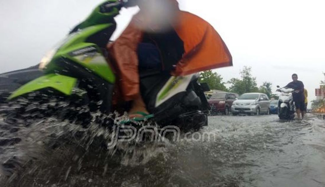 Pengendara melewati genangan air yang membanjiri Jalan AP Pettarani, Makassar, Sulsel, Jumat (18/12). Hujan deras dan buruknya drainase menyebabkan banjir di sejumlah kawasan di kota Makassar. Foto: M Idham/FAJAR/JPNN.com - JPNN.com