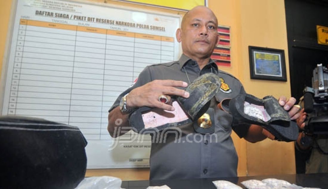 Seorang petugas menunjukan mengekspose barang bukti sepatu yang dijadikan sebagai tempat menyimpan narkoba jenis pil ektasi di dalam tapak sepatu di Mapolda Sumatera Selatan, Minggu (20/12). Foto: Alhadi/Palembang Ekspres/JPNN.com - JPNN.com