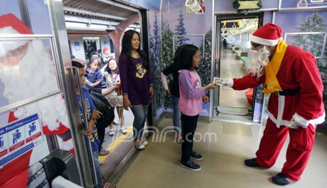 Sinterklas memberikan souvenir kepada penumpang KRL Commuter Line jurusan Jakarta Kota-Depok di Jakarta, Jumat (25/12). Dalam rangka memeriahkan Hari Natal dan menyambut tahun baru 2016 PT KAI Commuter Jabodetabek menghadirkan kereta bertemakan &acirc;€˜White Christmas&acirc;€™ dan menghadirkan tokoh Sinterklas. Foto: Ismail P/Indopos/JPNN.com - JPNN.com