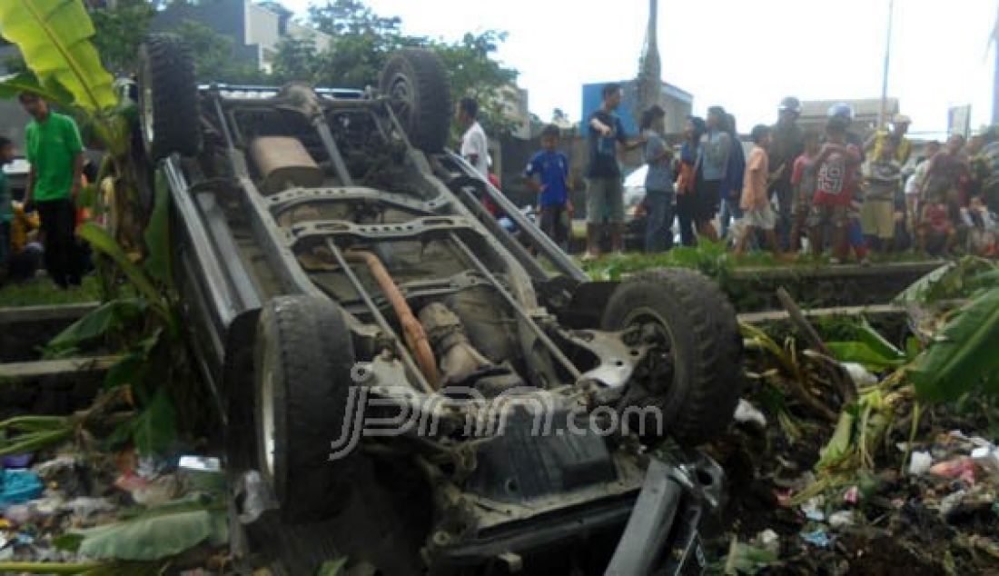 Mobil terbalik setelah menubruk sepeda motor yang terparkir di Jalan Cikurubuk Kota Tasikmalaya, Rabu (30/12). Foto: Rangga/Radar Tasikmalaya/JPNN.com - JPNN.com