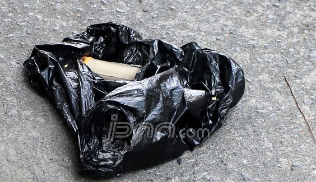 Barang yang diduga menyerupai bentuk bom yang terdapat dalam kantung plastik hitam yang tergeletak di jalan Desa Bendungan, Kecamatan Kraton, Kabupaten Pasuruan, Selasa (5/1) siang. Foto: Zubaidillah/Radar Bromo/JPNN.com - JPNN.com