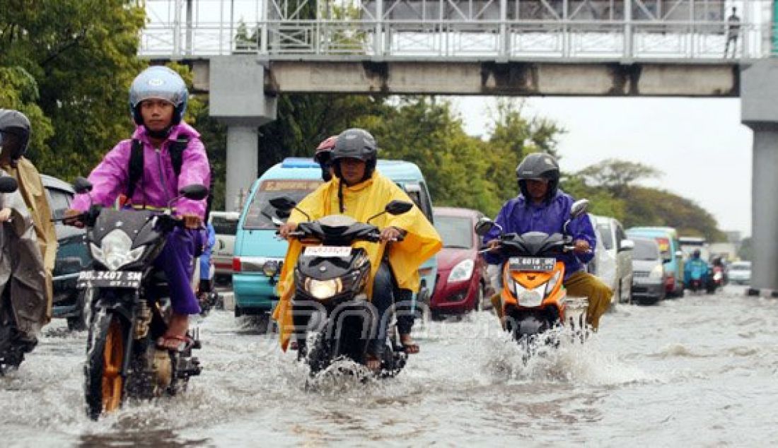 Pengguna jalan menerobos genangan air di badan jalan, di Jalan AP Pettarani, Makassar, Jumat, (22/1). Genangan air tersebut terjadi setiap hujan akibat drainase yang tidak berfungsi dengan baik di jalan tersebut. Foto: Yusuf/FAJAR/JPNN.com - JPNN.com