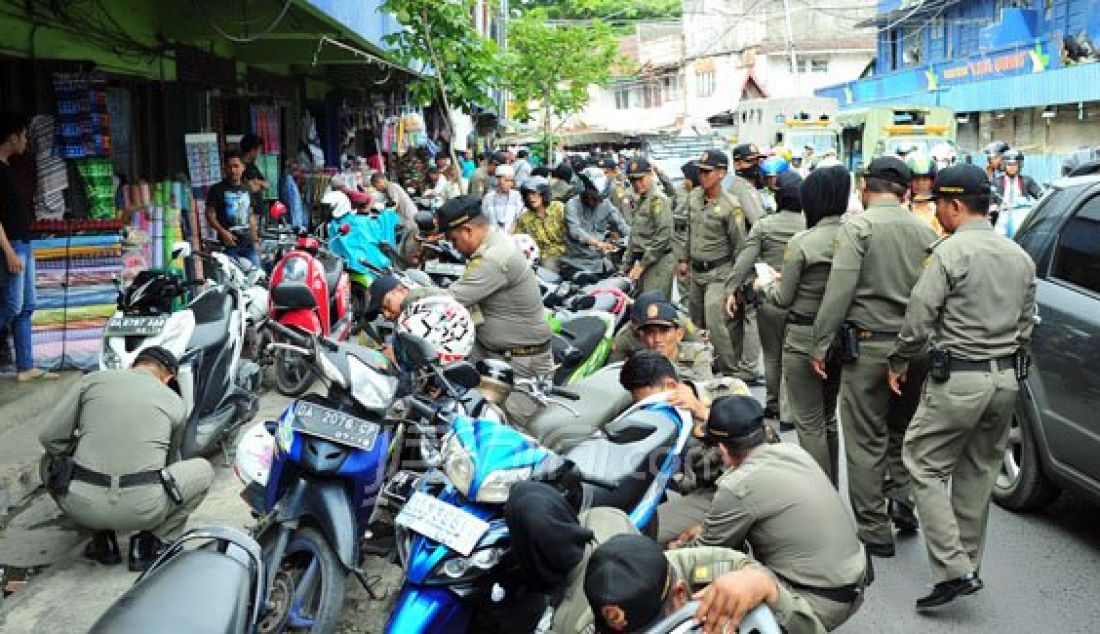 Ratusan personil Satpol PP menyerbu Jalan Ujung Murung, Pasar Sudimampir, Selasa (2/2). Puluhan sepeda motor yang parkir sembarangan di atas trotoar digembosi. Foto: Syarafuddin/Radar Banjarmasin/JPNN.com - JPNN.com