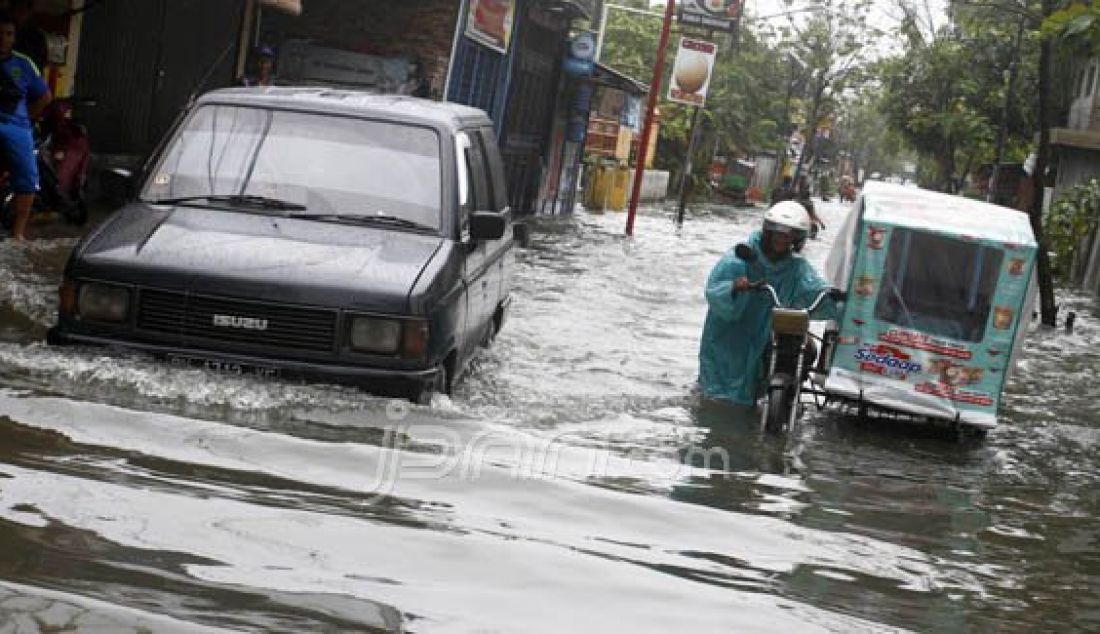 Kendaraan berusaha menerobos banjir yang menggenang Jalan Titi Papan Medan, Senin (8/2). Dampak buruknya saluran drainase dikawasan tersebut, mengakibatkan sejumlah jalan protokol tergenang saat hujan mengguyur kota Medan. Foto: Danil/Sumut Pos/JPNN.com - JPNN.com