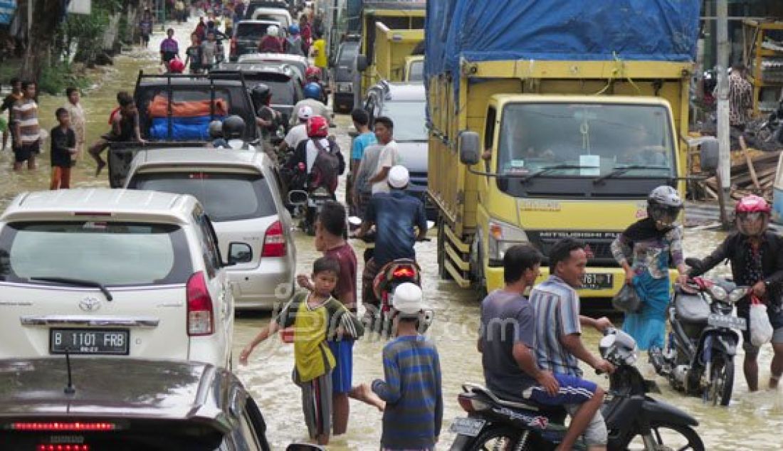 Terendam, sejumlah pengendara mendorong sepeda motornya yang terjebak banjir dijalan raya blega, kemarin (11/02) yang merupakan jalan Provinsi di Kab. Bangkalan. Foto: Allex/Radar Madura/JPNN.com - JPNN.com
