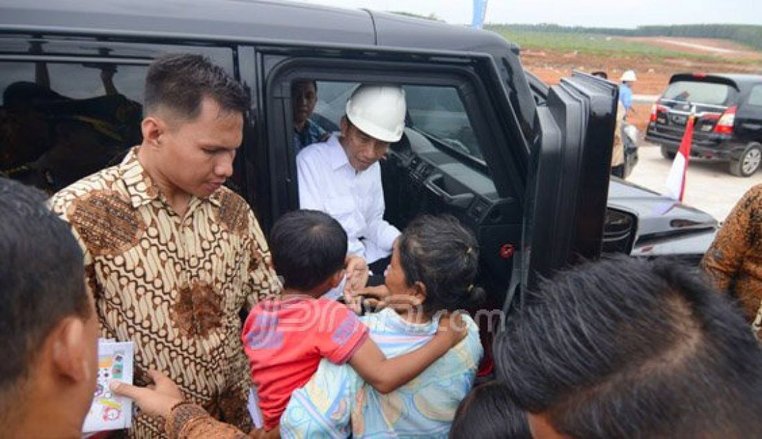 Presiden Joko Widodo dari dalam mobil membagikan buku tulis merah putih kepada warga saat mengunjungi Desa Sabah Balau Lampung Selatan, kemarin (11/2). Foto: Tegar/Radar Lampung/JPNN.com - JPNN.com