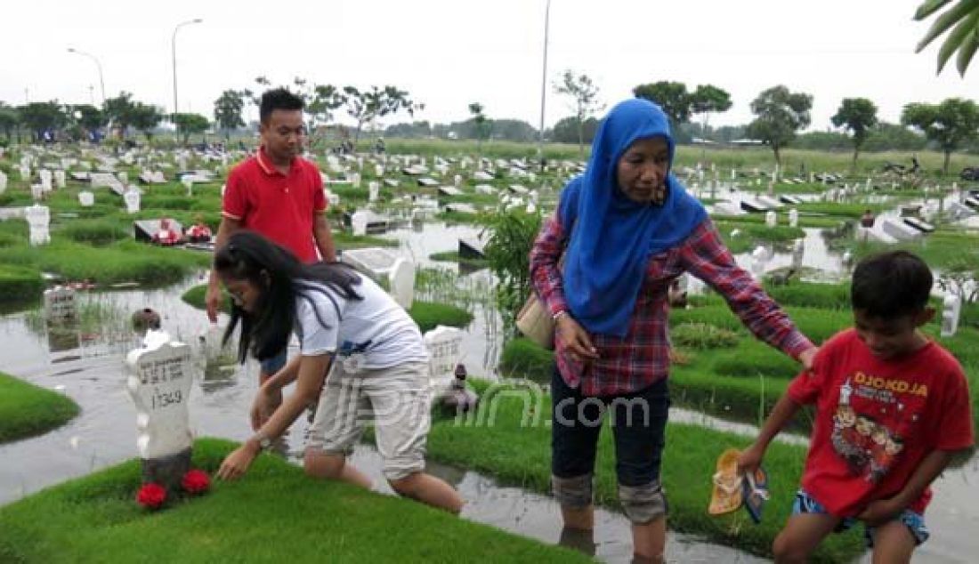 Salah satu keluarga berziarah di Tempat Pemakaman Umum Keputih Sukolilo yang tergenang banjir, Jumat (12/2). Foto: Satria/Radar Surabaya/JPNN.com - JPNN.com