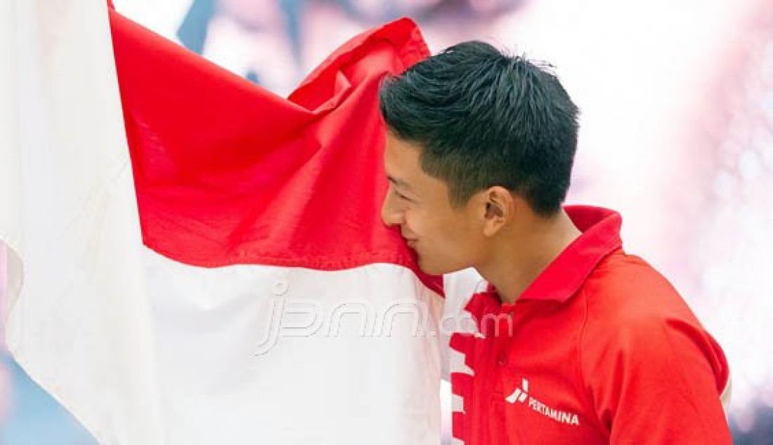 Pembalap Indonesia Rio haryanto mengibarkan dan mencium bendera merah putih saat konfrensi pers bergabungnya Rio di tim Manor Racing di Kantor Pertamina Pusat, Jakarta, Kamis (18/2). Foto: Wahyudin/Jawa Pos/JPNN.com - JPNN.com