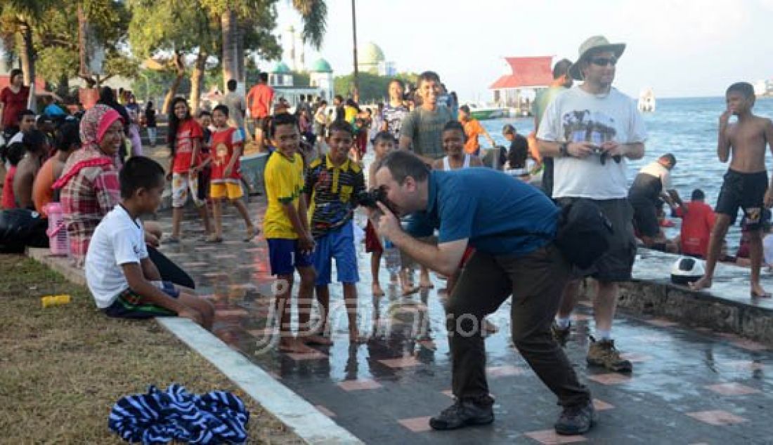 RAMNAI: Turis Asing terlihat sedang mengambil gambar seorang anak yang ada di kawasan pantai Swering, Ternate, Senin (7/3). Turis yang datang ke kota Ternate untuk mengaksikan langsung fenomena alam Gerhana Matahari Total (GMT). Foto: Erwin/Malut Pos/JPNN.com - JPNN.com