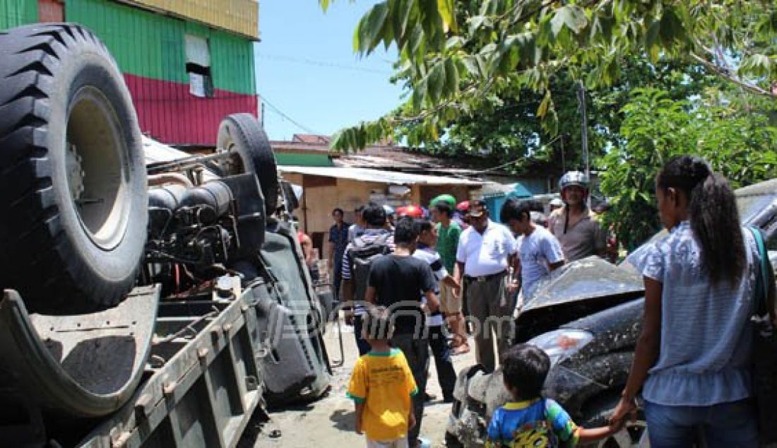 Sejumlah warga melihat kondisi truk milik Denzipur X/KYD yang terbalik di eks Terminal Lama setelah menabrak 3 mobil dan satu warung kopi, Jumat (11/3) pukul 10.45 WIT. Foto: Pratiwi/Cepos/JPNN.com - JPNN.com