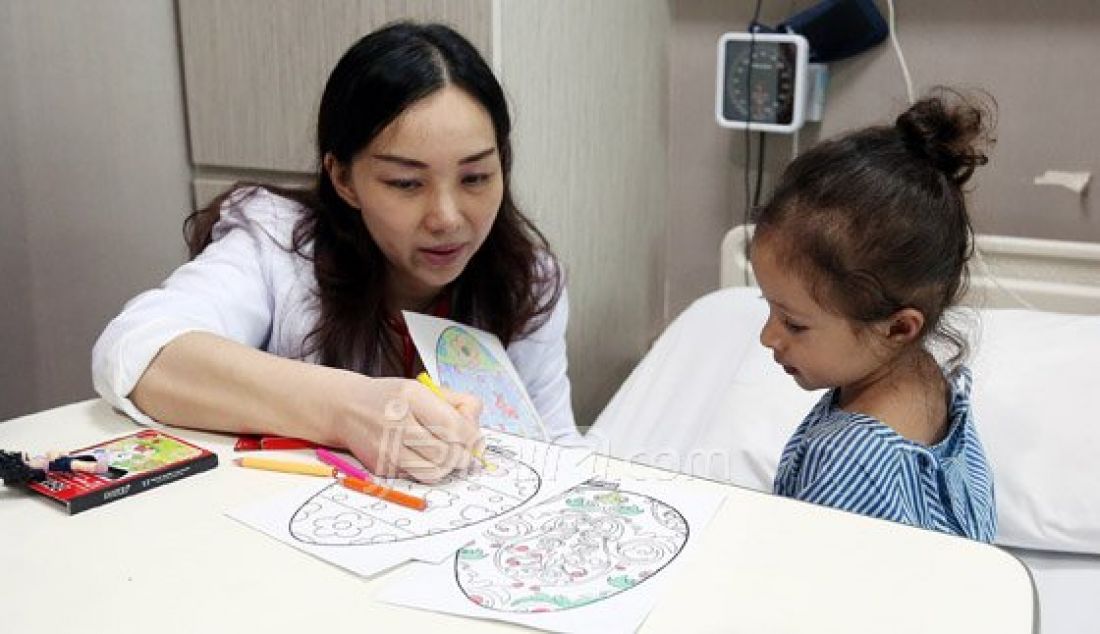 Dokter membimbing seorang anak untuk mewarnai gambar telur Paskah saat menjalani rawat inap di RS Siloam Simatupang, Jakarta Selatan, Minggu (27/3). Kegiatan mewarnai telur untuk menghibur pasien bertema &quot;Stress Relief&quot; ini merupakan program Inisiatif Pasien-Sentris guna membantu pemulihan. Foto : Ricardo/JPNN.com - JPNN.com