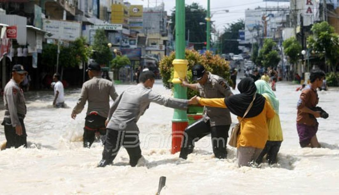 Anggota Sat Brimob Polda Babel membantu menyebrangi warga yang melintas daerah banjir di jalan Mayor Syafrie kota Pangkalpinang, Selasa (29/3). Foto: Budi/Babel Pos/JPNN.com - JPNN.com