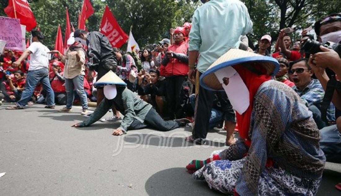 Buruh saat melakukan aksi teatherikal pada peringatan MAYDAY 2016 di Jalan Medan Merdeka Barat, Jakarta, Minggu (1/5). Para buruh menolak upah murah dan meminta pencabutan PP no 78/2015 tentang pengupahan. Foto: Ricardo/JPNN.com - JPNN.com