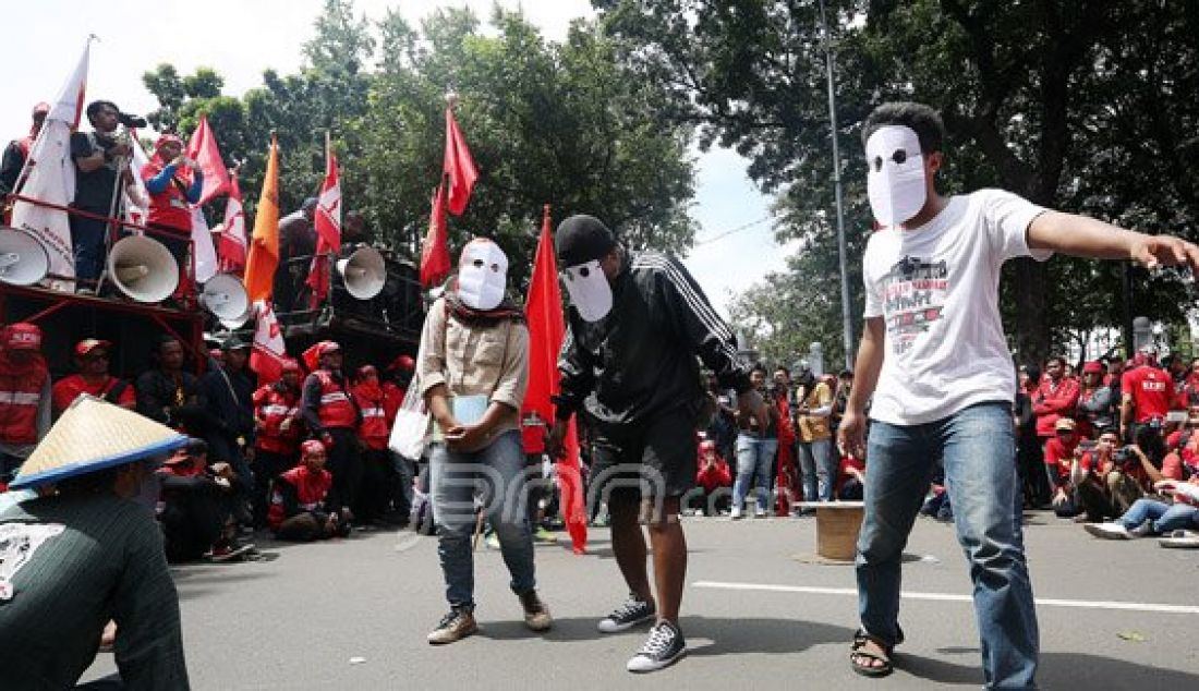 Buruh saat melakukan aksi teatherikal pada peringatan MAYDAY 2016 di Jalan Medan Merdeka Barat, Jakarta, Minggu (1/5). Para buruh menolak upah murah dan meminta pencabutan PP no 78/2015 tentang pengupahan. Foto: Ricardo/JPNN.com - JPNN.com