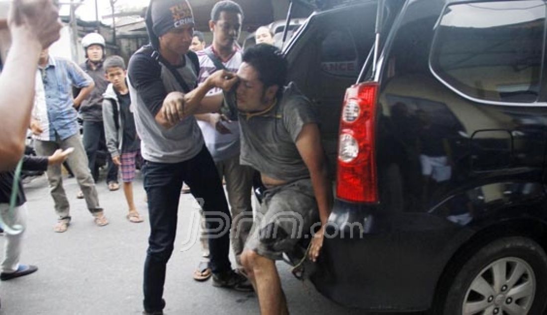 BURON: Caca Gurning saat digelandang oleh pihak kepolisian Polresta Pekanbaru saat dibawa ke Rs Bhayangkara, Pekanbaru, Riau (4/5). Untuk membekuk pelaku, petugas terpaksa memuntahkan timah panas di salah satu kaki tersangka. Foto: M Akhmad/Riau Pos/JPNN.com - JPNN.com