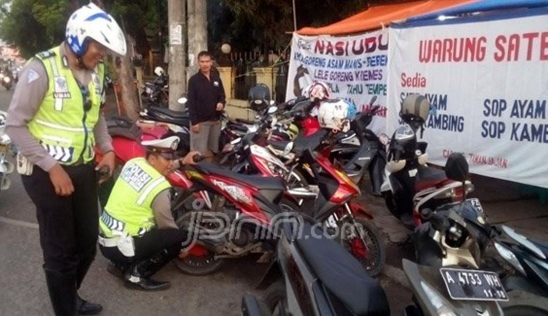Anggota Polres Serang saat menggembosi ban motor para pengendara yang parkir sembarangan di area terlarang di Jalan Ahmad Yani, Kota Serang, Senin (23/5). Foto: Deni/Radar Banten/JPNN.com - JPNN.com