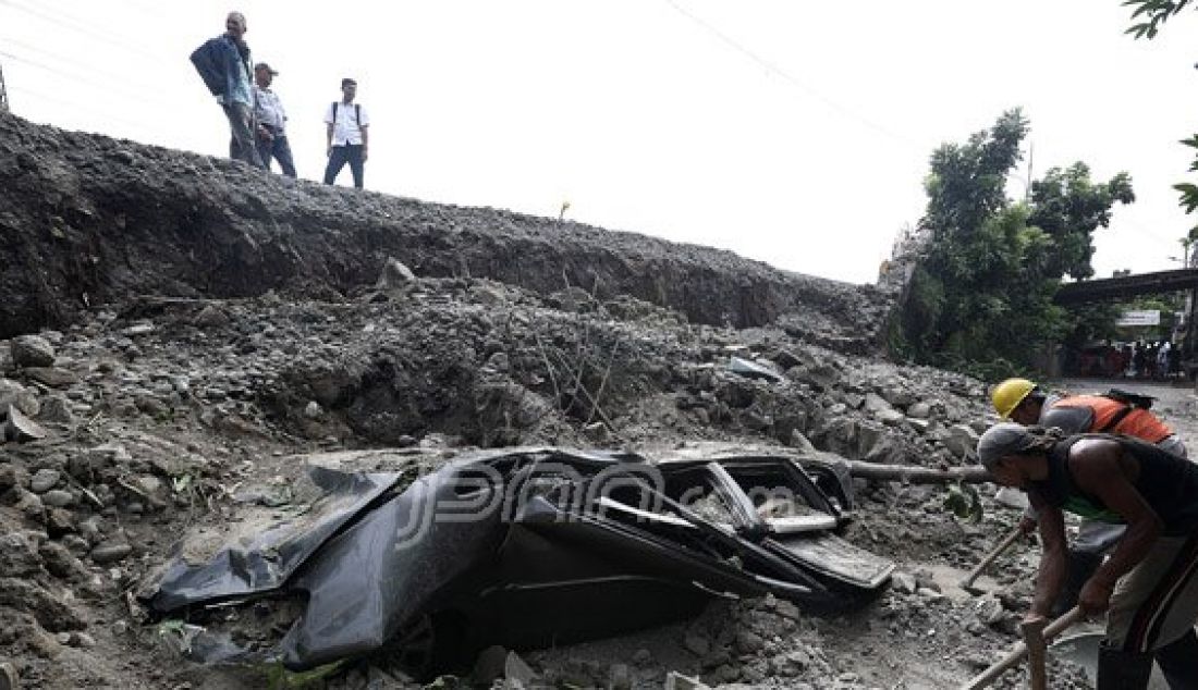 Sebuah mobil hancur tertimpa reruntuhan tembok pembatas jalan inspeksi Penghubung Kanal Banjir Barat, Duri Pulo, Gambir, Jakarta Pusat, Senin (13/6). Foto: Ricardo/JPNN.com - JPNN.com