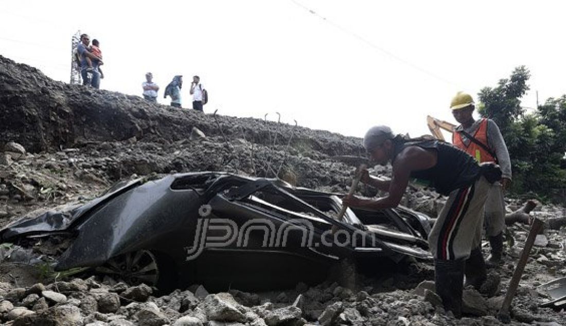 Sebuah mobil hancur tertimpa reruntuhan tembok pembatas jalan inspeksi Penghubung Kanal Banjir Barat, Duri Pulo, Gambir, Jakarta Pusat, Senin (13/6). Foto: Ricardo/JPNN.com - JPNN.com