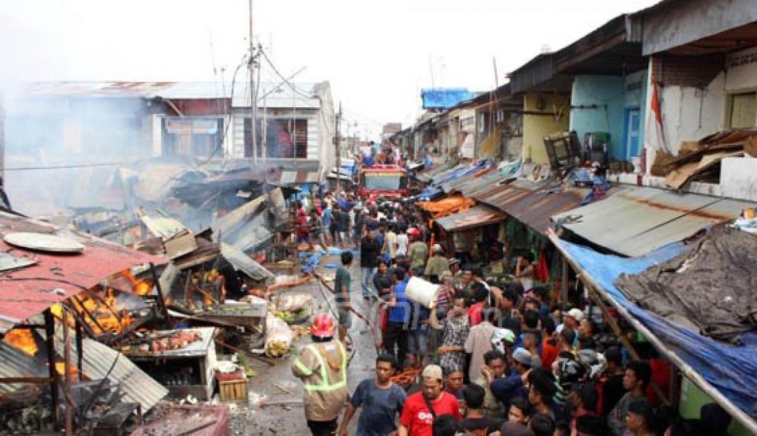 Pemadam kebakaran dibantu warga berusaha memadamkan api saat terjadi kebakaran di kawasan Pasar Pannampu, Makassar, Minggu (26/6). Puluhan kios dan tempat tinggal hangus terbakar. Foto: Ardiansyah/FAJAR - JPNN.com