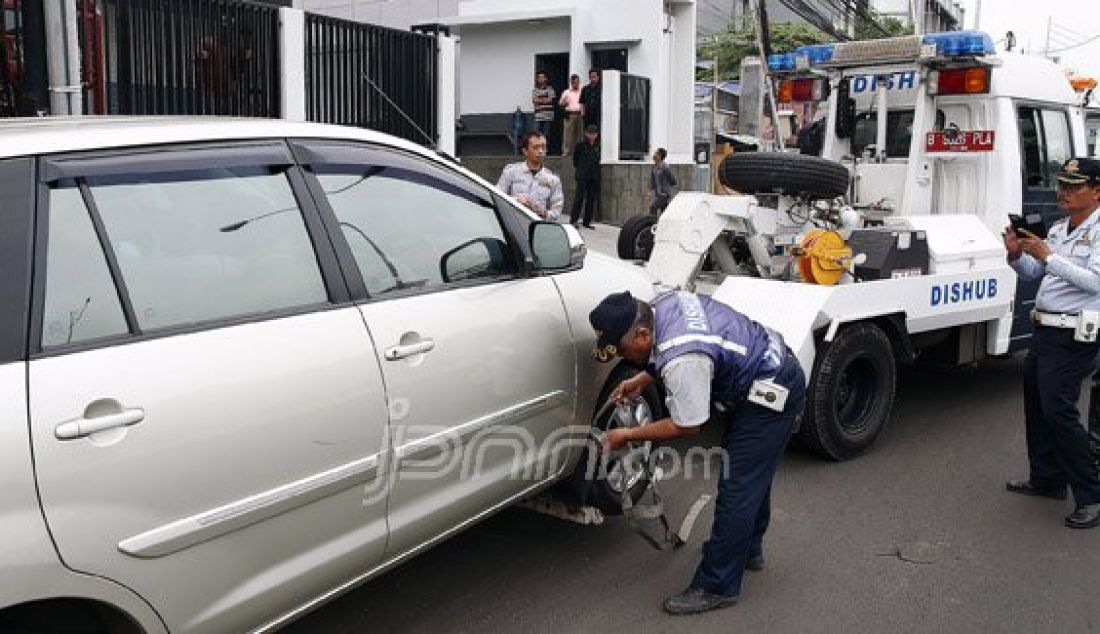 Petugas Dishub DKI memasang alat derek pada mobil yang parkir liar di kawasan Gunung Sahari, Jakarta, Selasa (28/6). Penertiban rutin ini dilakukan untuk membuat efek jera bagi warga yang masih parkir sembarangan. Foto : Ricardo/JPNN.com - JPNN.com