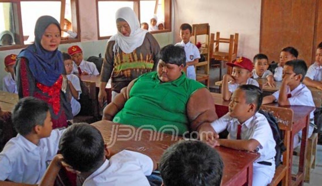 Arya Permana (10), bocah obesitas ekstrem asal Karawang, Jawa Barat disambut kawan-kawannya pada hari pertama sekolah di SDN Cipurwasari, Desa Cipurwasari, Kecamatan Pangkalan Karawang, Senin (18/7). Foto: Indra/Bekasi Ekspres - JPNN.com