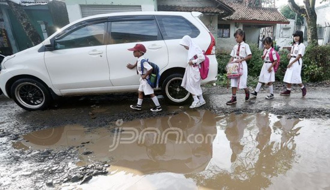 Sejumlah siswas-siwi Sekolah Dasar (SD) berjalan menghindari jalan rusak yang tergenang dengan air di Jl Nanggerang, Tajurhalang, Kabupaten Bogor, Selasa (19/7). Foto: Ricardo/JPNN.com - JPNN.com