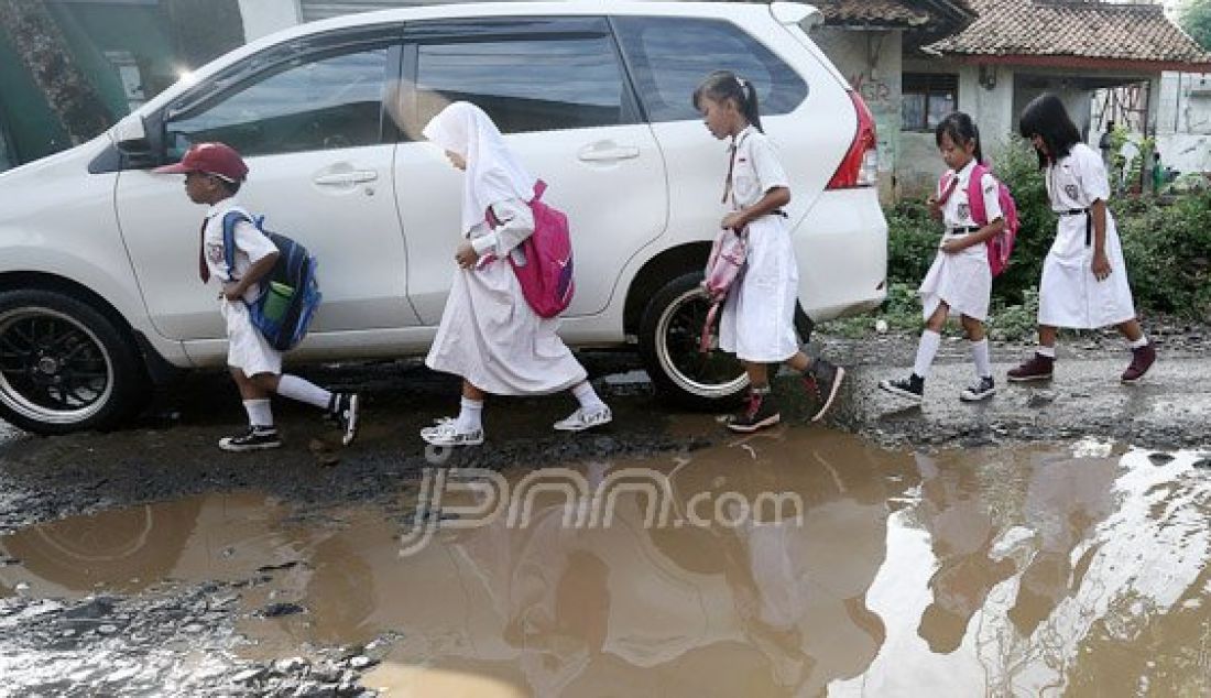 Sejumlah siswas-siwi Sekolah Dasar (SD) berjalan menghindari jalan rusak yang tergenang dengan air di Jl Nanggerang, Tajurhalang, Kabupaten Bogor, Selasa (19/7). Foto: Ricardo/JPNN.com - JPNN.com