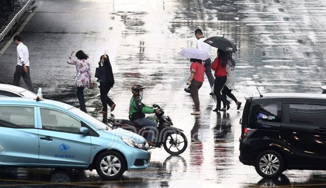 Sejumlah pejalan kaki menyebrangi Jl. MH Thamrin saat hujan deras mengguyur kawasan Sarinah Thamrin, Jakarta, Rabu (20/7). Menurut Sub-Bidang Informasi Meteorologi BMKG. musim kemarau tahun ini akan mundur dari siklus musim kemarau pada umumnya. Foto: Ricardo/JPNN.com - JPNN.com