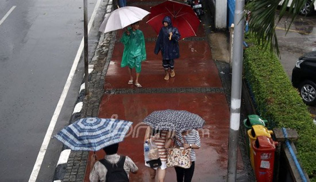 Sejumlah pejalan kaki menyebrangi Jl. MH Thamrin saat hujan deras mengguyur kawasan Sarinah Thamrin, Jakarta, Rabu (20/7). Menurut Sub-Bidang Informasi Meteorologi BMKG. musim kemarau tahun ini akan mundur dari siklus musim kemarau pada umumnya. Foto: Ricardo/JPNN.com - JPNN.com