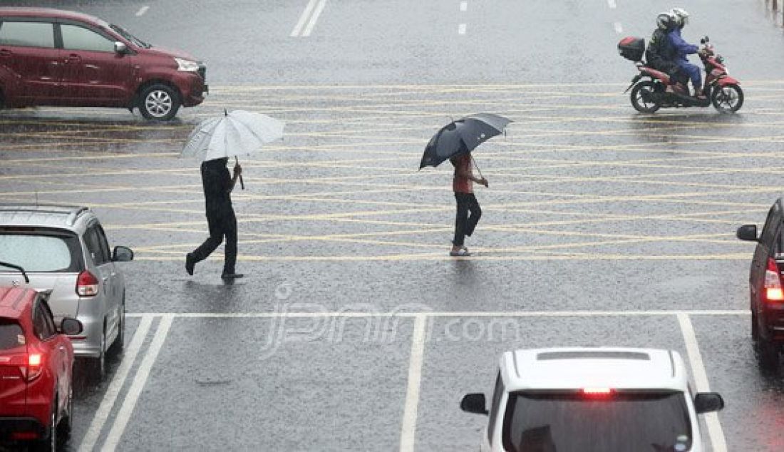 Sejumlah pejalan kaki menyebrangi Jl. MH Thamrin saat hujan deras mengguyur kawasan Sarinah Thamrin, Jakarta, Rabu (20/7). Menurut Sub-Bidang Informasi Meteorologi BMKG. musim kemarau tahun ini akan mundur dari siklus musim kemarau pada umumnya. Foto: Ricardo/JPNN.com - JPNN.com