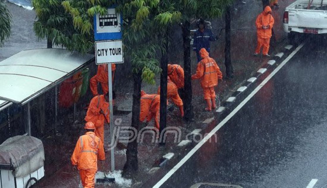 Sejumlah Petugas dari Dinas Kebersihan membuang genangan air kedalam selokan saat hujan deras di kawasan Jl MH Thamrin, Jakarta, Rabu (20/7). Tingginya curah hujan yang mengguyur kawasan Sarinah membuat genangan disisi jalan dan trotoar. Foto : Ricardo/JPNN.com - JPNN.com