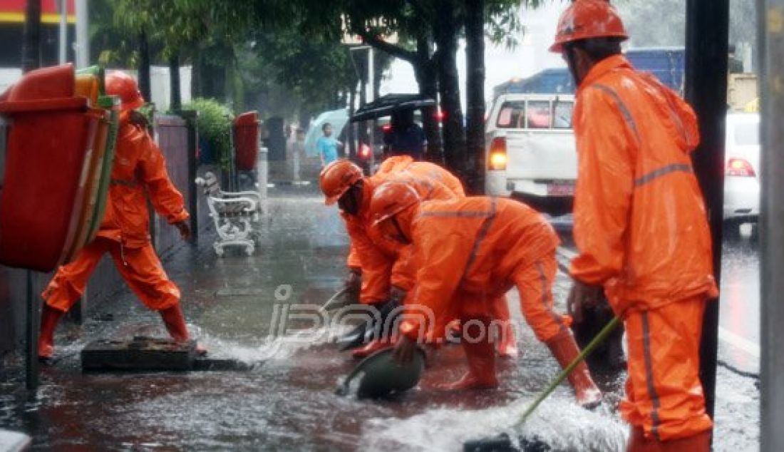 Sejumlah Petugas dari Dinas Kebersihan membuang genangan air kedalam selokan saat hujan deras di kawasan Jl MH Thamrin, Jakarta, Rabu (20/7). Tingginya curah hujan yang mengguyur kawasan Sarinah membuat genangan disisi jalan dan trotoar. Foto : Ricardo/JPNN.com - JPNN.com