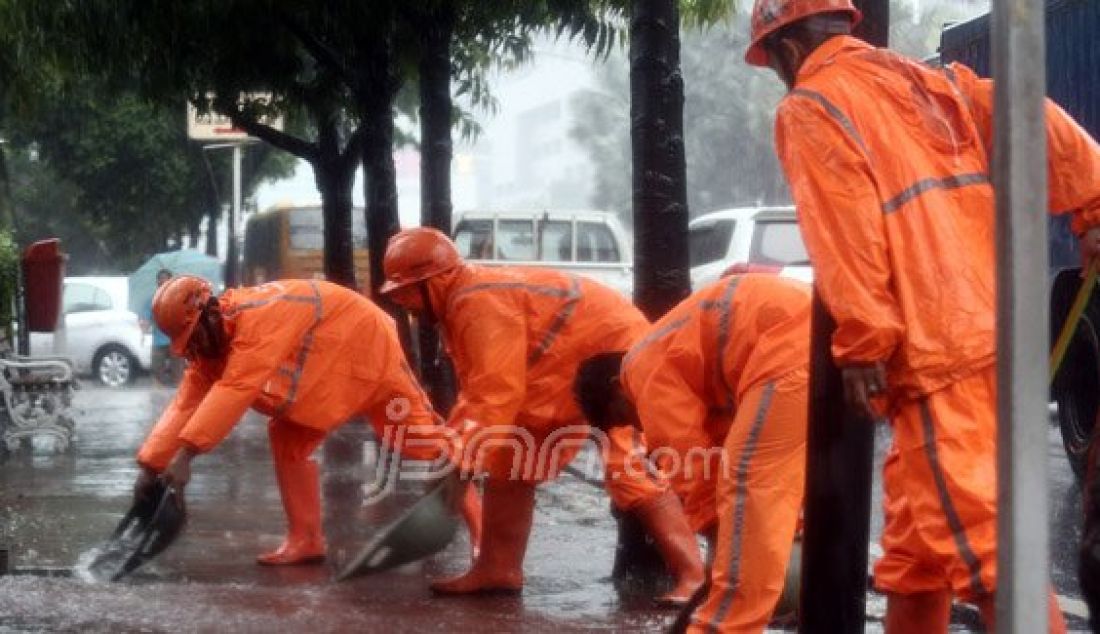 Sejumlah Petugas dari Dinas Kebersihan membuang genangan air kedalam selokan saat hujan deras di kawasan Jl MH Thamrin, Jakarta, Rabu (20/7). Tingginya curah hujan yang mengguyur kawasan Sarinah membuat genangan disisi jalan dan trotoar. Foto : Ricardo/JPNN.com - JPNN.com