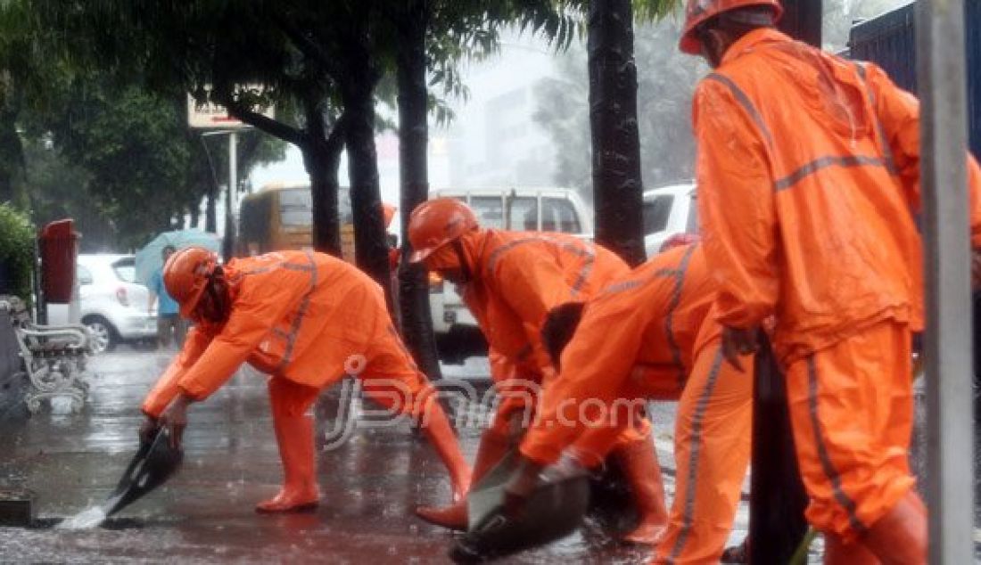 Sejumlah Petugas dari Dinas Kebersihan membuang genangan air kedalam selokan saat hujan deras di kawasan Jl MH Thamrin, Jakarta, Rabu (20/7). Tingginya curah hujan yang mengguyur kawasan Sarinah membuat genangan disisi jalan dan trotoar. Foto : Ricardo/JPNN.com - JPNN.com