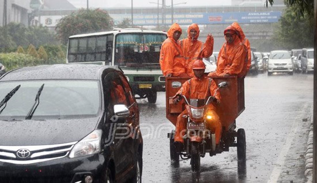 Sejumlah Petugas dari Dinas Kebersihan membuang genangan air kedalam selokan saat hujan deras di kawasan Jl MH Thamrin, Jakarta, Rabu (20/7). Tingginya curah hujan yang mengguyur kawasan Sarinah membuat genangan disisi jalan dan trotoar. Foto : Ricardo/JPNN.com - JPNN.com