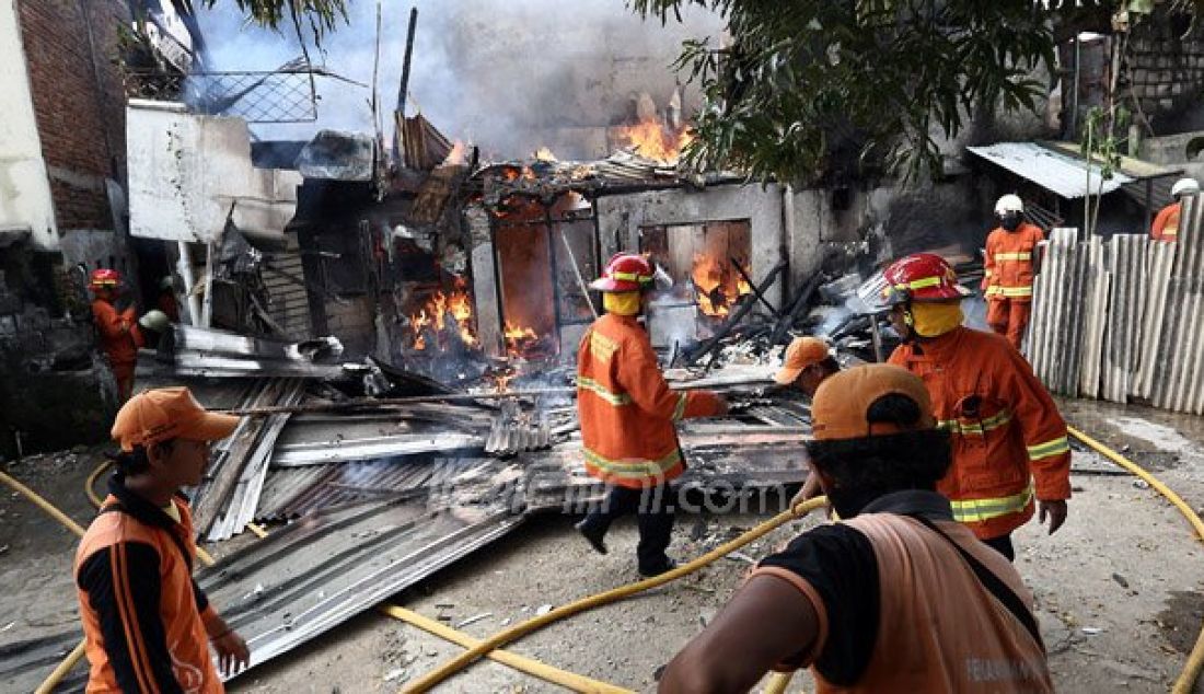 Petugas pemadam kebakaran bersama warga berusaha memadamkan api yang menghanguskan pemukiman penduduk di Jalan Kp Duku, Kebayoran Lama, Jakarta, Jumat (5/8). Empat unit mobil pemadam diterjunkan dalam kebakaran yang diduga akibat korsleting listrik. Foto: Ricardo/JPNN.com - JPNN.com