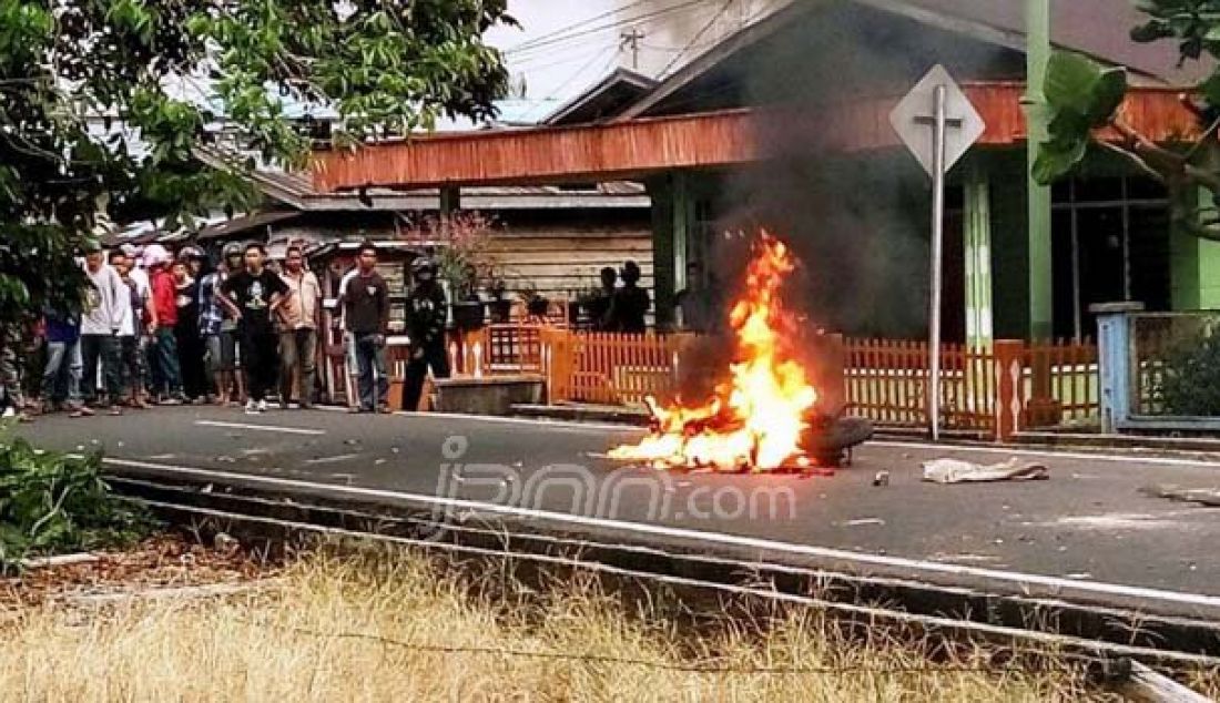DIBAKAR: Massa melihat Sepeda motor milik anggota polisi terbakar di Jalan Pembangunan II Selatpanjang, Kepulauan Meranti, Riau, Kamis (25/8). Foto: Ahmad/Riau Pos - JPNN.com