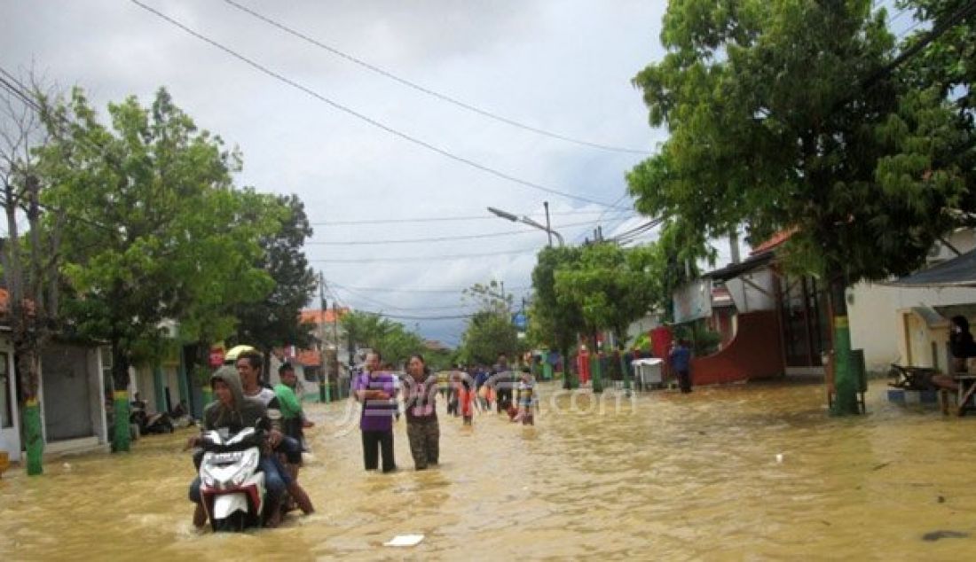 Sejumlah warga mencoba menerobos banjir yang melumpuhkan kawasan kota Sampang, Madura, Minggu (25/9). Foto: Radar Madura - JPNN.com