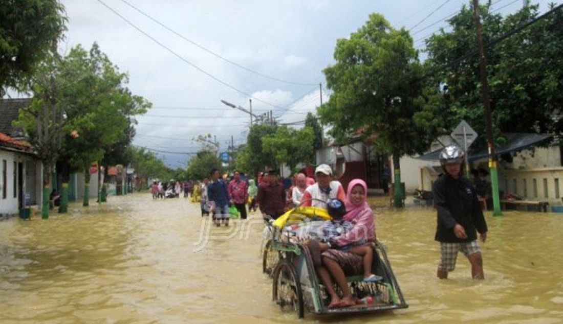 Sejumlah warga mencoba menerobos banjir yang melumpuhkan kawasan kota Sampang, Madura, Minggu (25/9). Foto: Radar Madura - JPNN.com