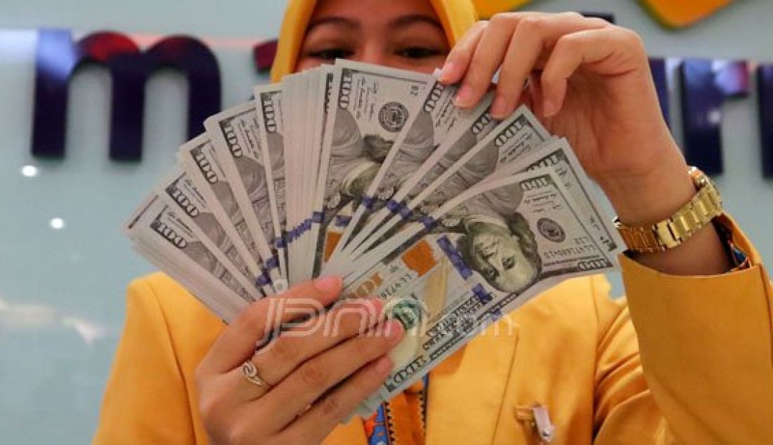 Teller Bank Mandiri menghitung mata uang Dollar di Jakarta, Selasa (27/9). Nilai tukar rupiah hingga perdagangan Selasa (27/9) siang menguat ke kisaran Rp 12.900 per-Dollar Di pasar spot, rupiah diperdagangkan pada level Rp 12.936 per-Dollar AS. Foto: Raka/Jawa Pos - JPNN.com