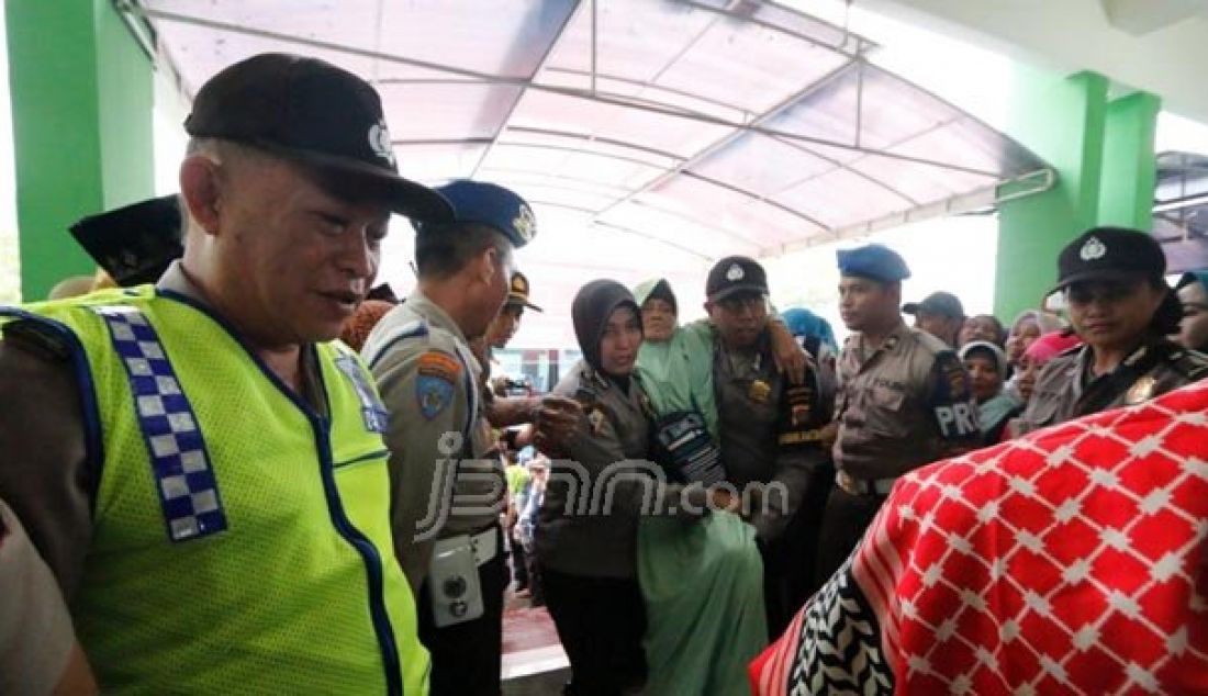 Petugas Kepolisian mengangkat salah seorang jamaah Haji saat tiba di masjid Agung An-Nur, Jumat (29/9). Sebanyak 151 jemaah haji Banggai tiba dengan selamat di kota Luwuk, sekira pukul 15.30 WITA. Foto: M Taufik/Luwuk Po - JPNN.com