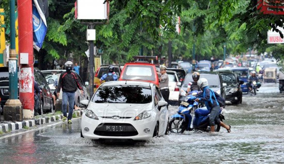 BANJIR: Kendaraan bermotor melintas genangan air yang membanjiri jalan Dr Mansur Medan, Kamis (30/9). Banjir tersebut disebabkan hujan deras pada hari sebelumnya dan buruknya saluran drainase. Foto: Sutan/Sumut Pos - JPNN.com
