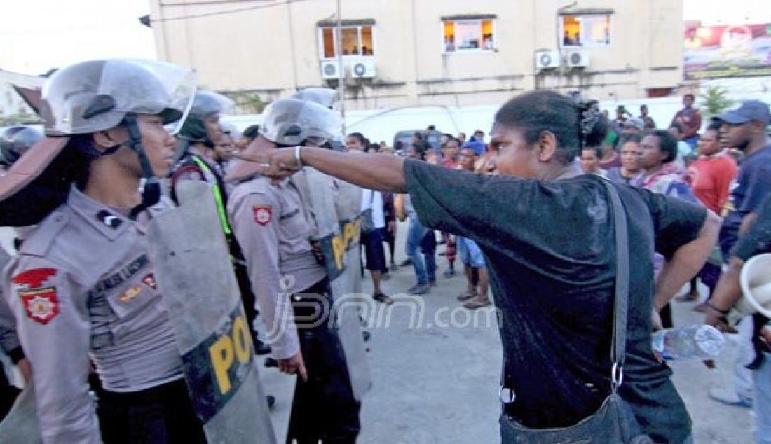 Seorang Mama-mama Papua menunjuk muka seorang Polisi yang sedang melakukan pengamanan di halaman Pengadilan Negeri Jayapura pasca penundaan sidang pembacaan tuntutan, Rabu (5/10). Foto: Gamel/Cendrawasih Pos - JPNN.com