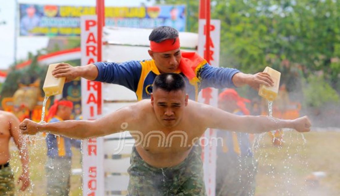 Seorang Prajurit Batalyon Infanteri Para Raider 501/Bajra Yudha mengguyur tubuh rekanya dengan air keras dalam atraksi sertijab Komandan Batalyon Infanteri Para Raider 501/Bajra Yudha, Minggu (23/10). Foto : WS Hendro/ Radar Madiun/JPNN - JPNN.com