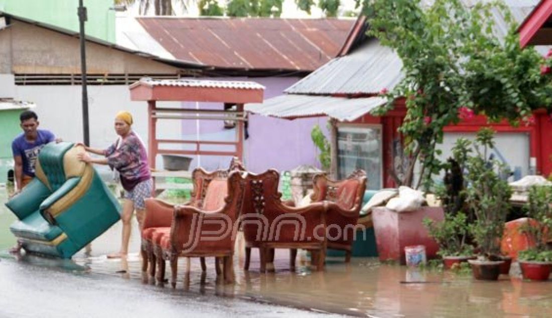 Warga Desa Tenilo, Kecamatan Limboto Barat, Kabupaten Gorontalo membersihkan perabot rumah tangga yang terendam banjir bandang, Rabu (26/10). Foto: Jalal/Gorontalo Post - JPNN.com