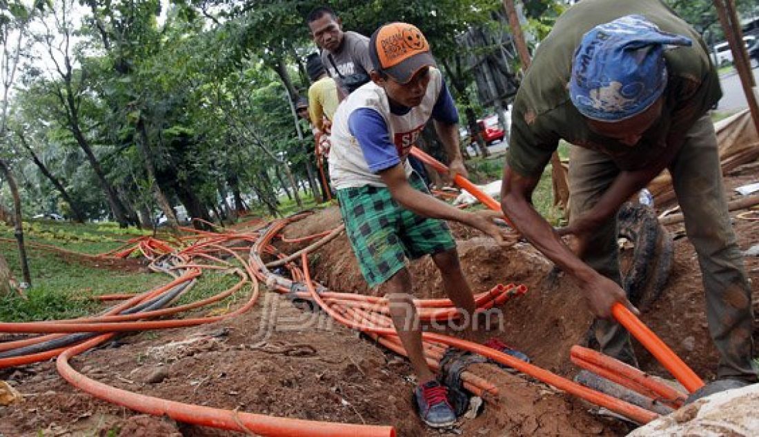 Pekerja saat memasang kabel instalasi fiber optik bawah tanah (fiber optic) di Kawasan Kebon Jeruk, Jakarta Barat, Kamis (22/12). Sistem telepon, sistem TV kabel serta jaringan Internet yang menggunakan media instalasi fiber optik bawah tanah ini terus di - JPNN.com