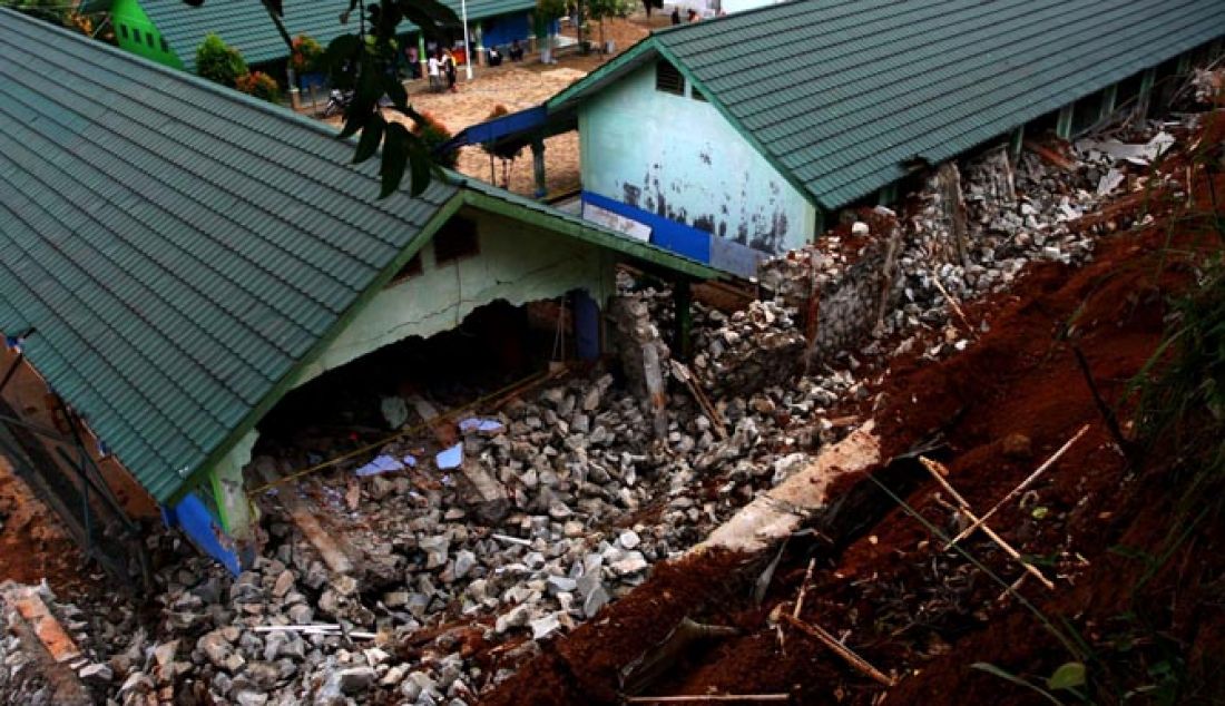 Warga melihat bangunan sekolah yang hancur tertimpa longsoran tanah dan turap di SMP 19 Tangsel Ciater, Tangerang Selatan, Rabu (4/1) Longsor yang disebabkan karena hujan deras yang mengguyur kawasan tersebut serta adanya pengerukan tanah menimpa lima ruang kelas SMP 19 yang mengalami rusak parah. - JPNN.com